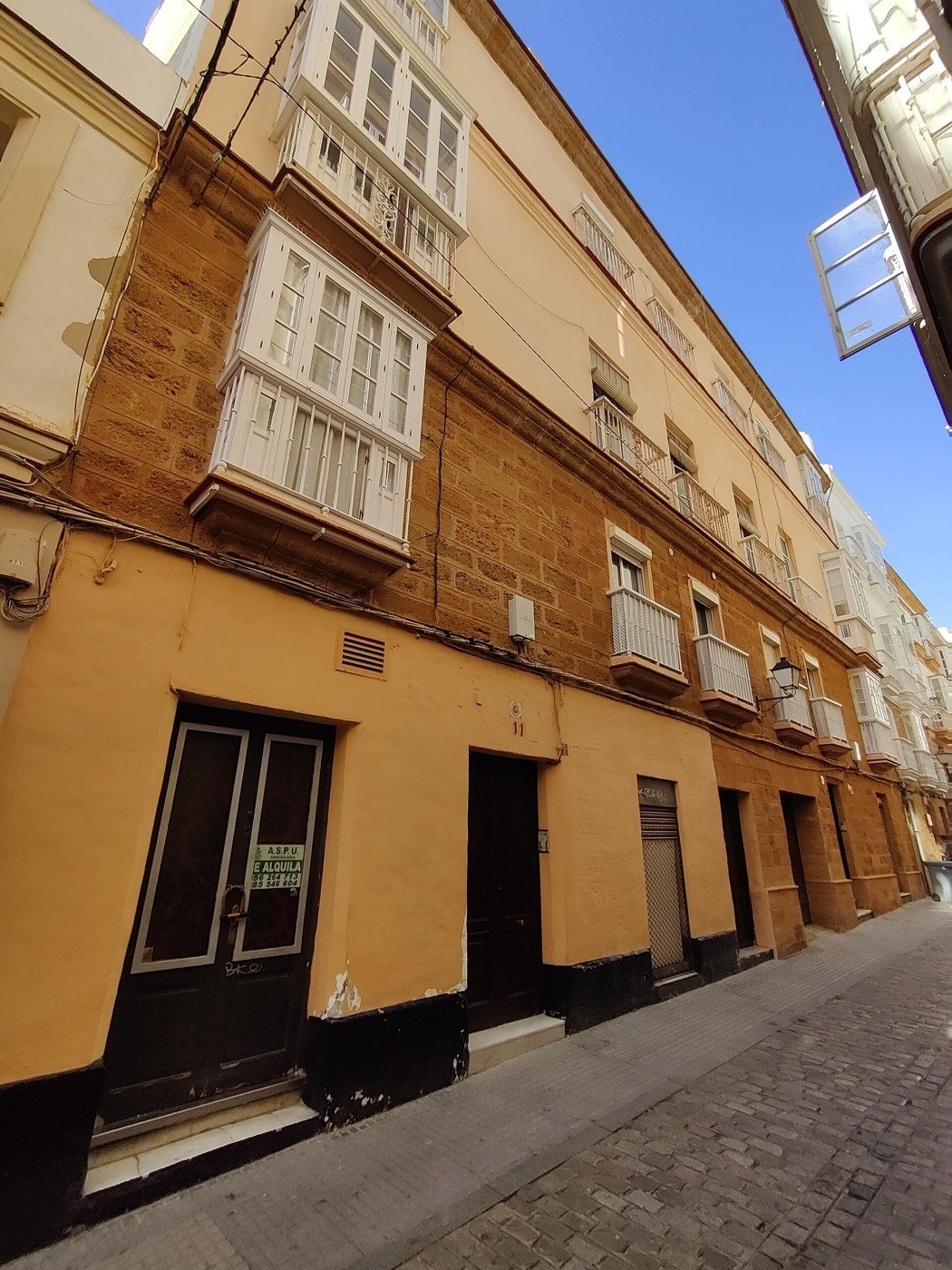 Fachada de un edificio de viviendas con miradores blancos en la calle Rosario de Cádiz